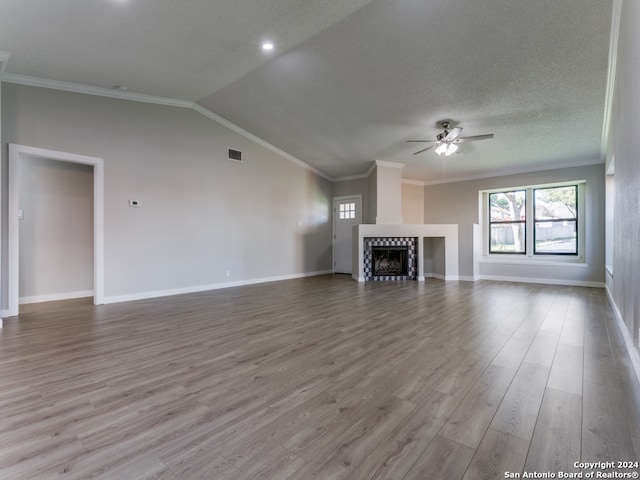 unfurnished living room with ceiling fan, crown molding, wood-type flooring, vaulted ceiling, and a tiled fireplace