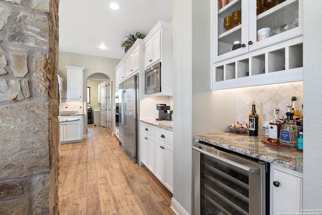 kitchen featuring white cabinetry, beverage cooler, light stone counters, light hardwood / wood-style flooring, and appliances with stainless steel finishes