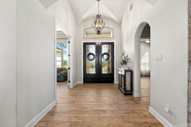 entrance foyer featuring french doors, light hardwood / wood-style floors, an inviting chandelier, and lofted ceiling