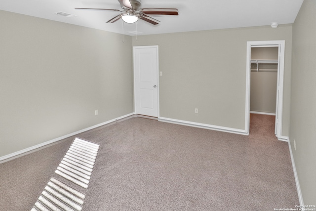 unfurnished bedroom with ceiling fan, light colored carpet, a walk in closet, and a closet