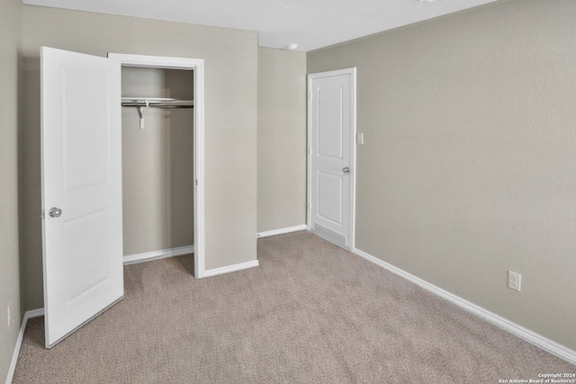 unfurnished bedroom with light colored carpet and a closet