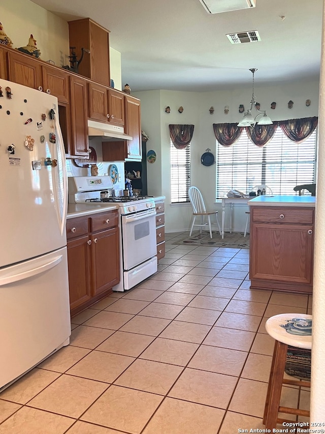 kitchen with decorative light fixtures, white appliances, and light tile patterned floors