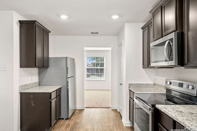 kitchen featuring dark brown cabinetry, stainless steel appliances, and light wood-type flooring