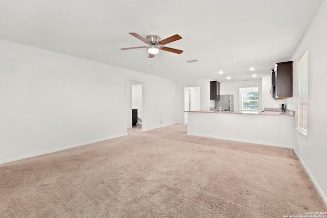 unfurnished living room with ceiling fan and light colored carpet