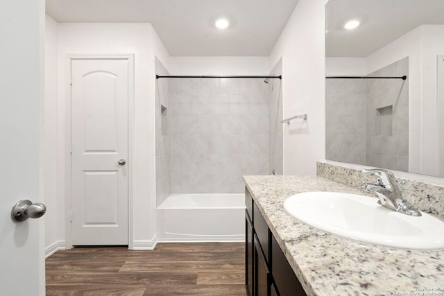 bathroom with hardwood / wood-style floors, vanity, and tiled shower / bath combo