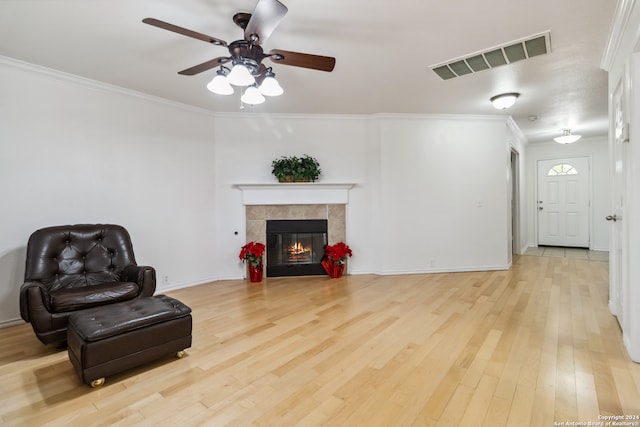 sitting room with a fireplace, light hardwood / wood-style flooring, ceiling fan, and crown molding