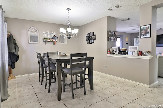 tiled dining space featuring ceiling fan with notable chandelier and a textured ceiling