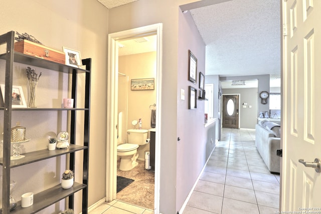 hall featuring light tile patterned floors and a textured ceiling