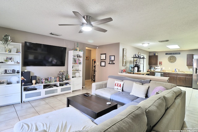 tiled living room with ceiling fan, sink, and a textured ceiling