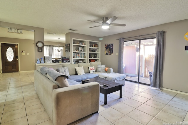 living room featuring ceiling fan with notable chandelier, a textured ceiling, built in features, and light tile patterned flooring