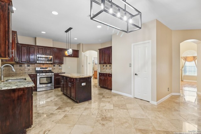 kitchen with decorative backsplash, stainless steel appliances, a kitchen island, and sink