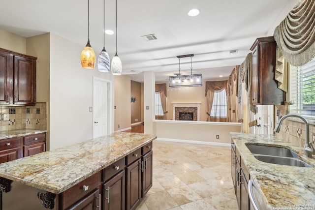 kitchen featuring backsplash, light stone counters, sink, and a kitchen island