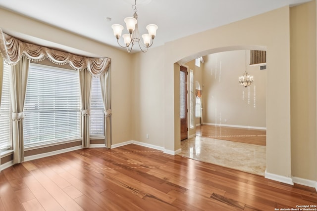 unfurnished room with hardwood / wood-style flooring and an inviting chandelier