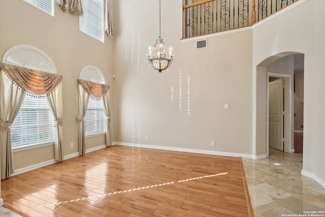 spare room featuring hardwood / wood-style floors, a chandelier, and a high ceiling