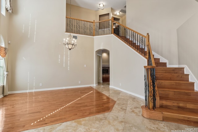 interior space featuring wood-type flooring, a high ceiling, and an inviting chandelier