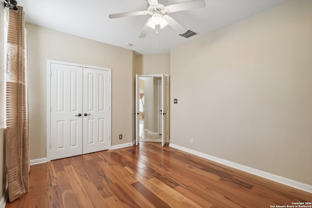 unfurnished bedroom featuring ceiling fan, a closet, and wood-type flooring