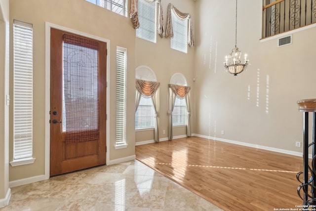 entryway with wood-type flooring, a towering ceiling, and an inviting chandelier