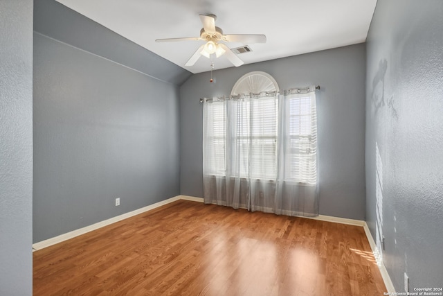 empty room with hardwood / wood-style flooring, ceiling fan, and vaulted ceiling