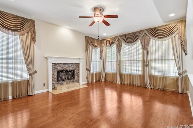 unfurnished living room featuring hardwood / wood-style floors, plenty of natural light, ceiling fan, and a fireplace