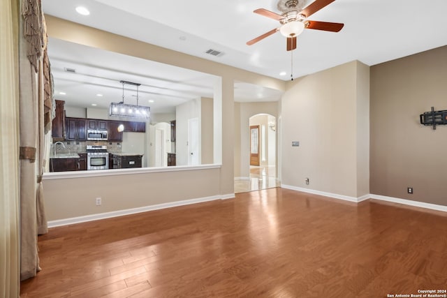 unfurnished living room with dark hardwood / wood-style floors, ceiling fan, and sink