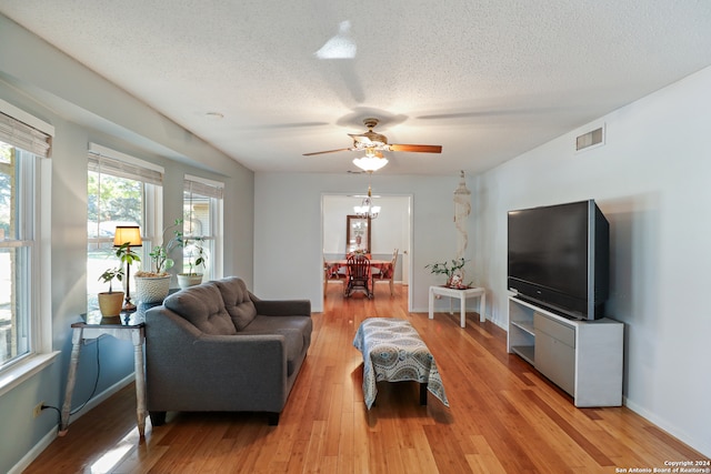 living room with ceiling fan, light hardwood / wood-style flooring, and a textured ceiling