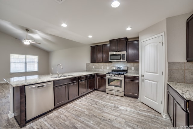 kitchen with sink, kitchen peninsula, vaulted ceiling, appliances with stainless steel finishes, and light wood-type flooring