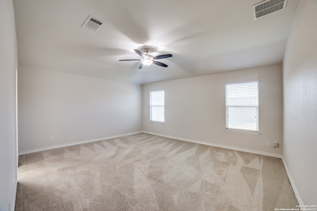 carpeted empty room with ceiling fan and plenty of natural light