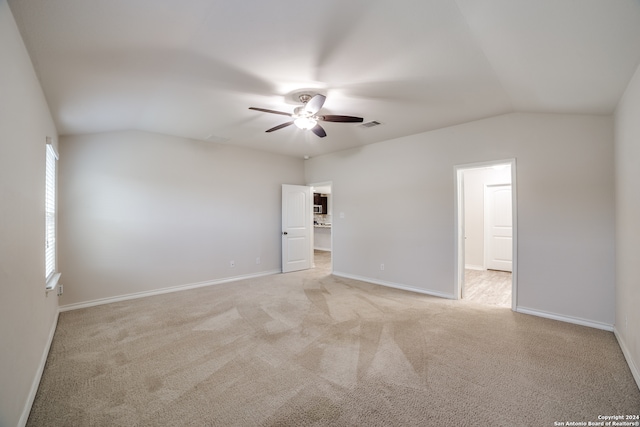 carpeted spare room with ceiling fan and vaulted ceiling