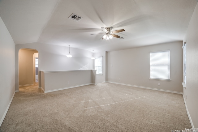 carpeted empty room with ceiling fan, a wealth of natural light, and vaulted ceiling