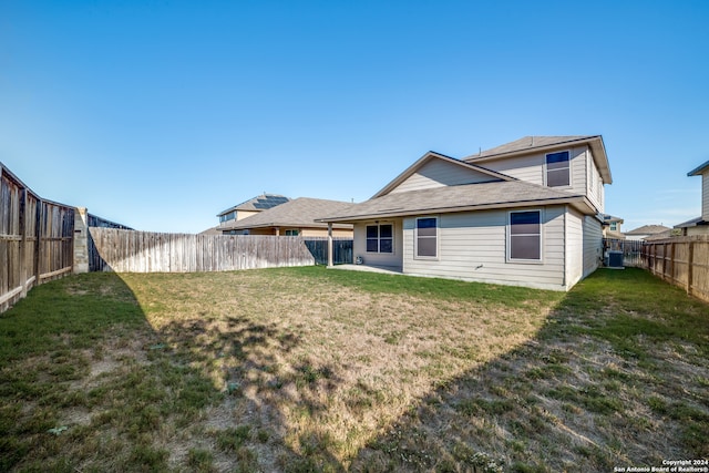 rear view of property featuring a yard and central AC unit