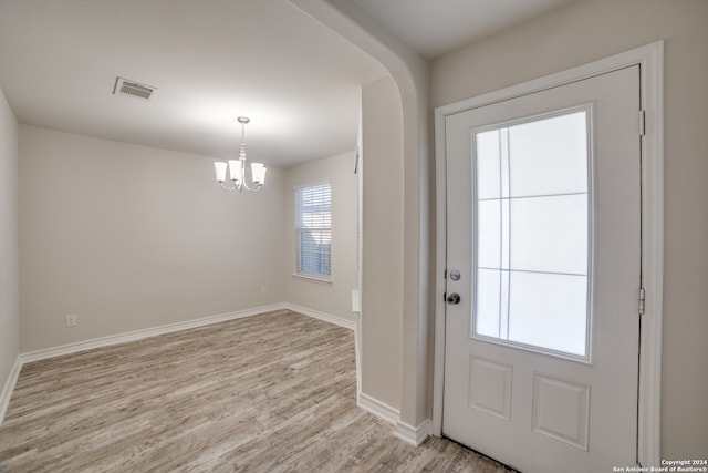 doorway featuring light hardwood / wood-style floors, an inviting chandelier, and a wealth of natural light