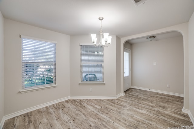 spare room with wood-type flooring and a notable chandelier