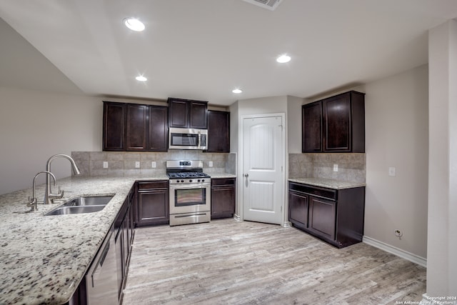 kitchen featuring light stone countertops, light hardwood / wood-style flooring, stainless steel appliances, and sink