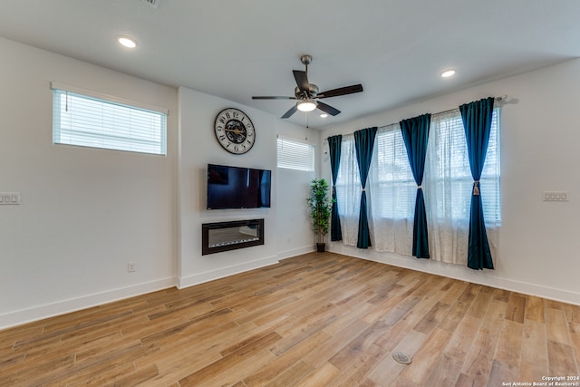 unfurnished living room featuring light hardwood / wood-style floors, ceiling fan, and a healthy amount of sunlight