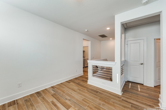 unfurnished room featuring washer / clothes dryer and hardwood / wood-style floors