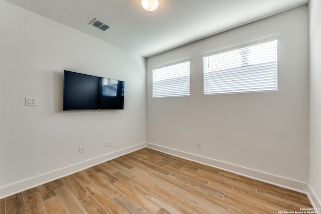 spare room with a textured ceiling and light hardwood / wood-style floors