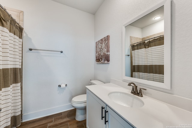 bathroom with wood-type flooring, vanity, toilet, and walk in shower