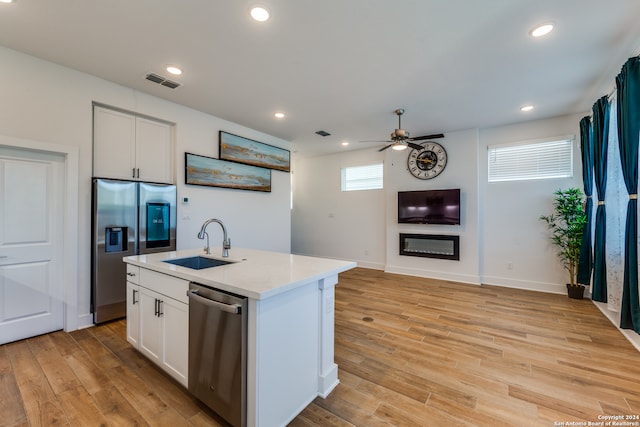 kitchen featuring light wood-type flooring, stainless steel appliances, sink, a center island with sink, and white cabinetry