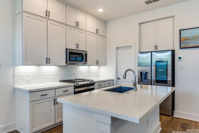 kitchen featuring dark hardwood / wood-style floors, sink, stainless steel appliances, and an island with sink