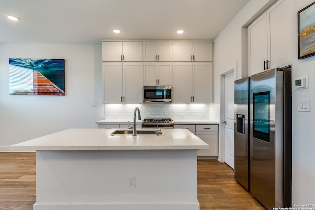 kitchen featuring white cabinets, sink, light hardwood / wood-style flooring, an island with sink, and appliances with stainless steel finishes