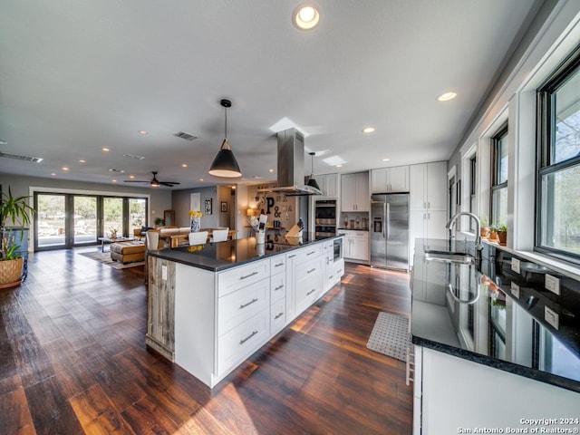 kitchen with sink, stainless steel refrigerator with ice dispenser, hanging light fixtures, white cabinetry, and island exhaust hood