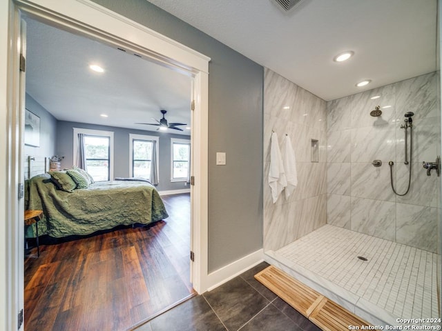 bathroom with hardwood / wood-style floors, a tile shower, and ceiling fan