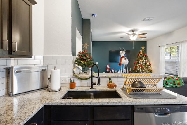 kitchen with light stone countertops, stainless steel dishwasher, and sink