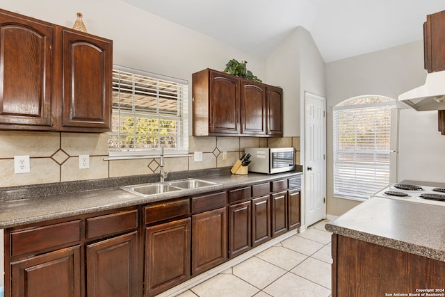 kitchen with sink, tasteful backsplash, white fridge, light tile patterned floors, and exhaust hood