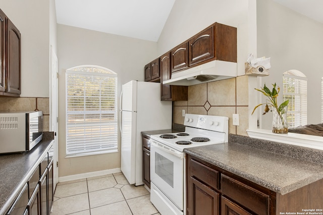 kitchen featuring lofted ceiling, white appliances, light tile patterned floors, and a healthy amount of sunlight