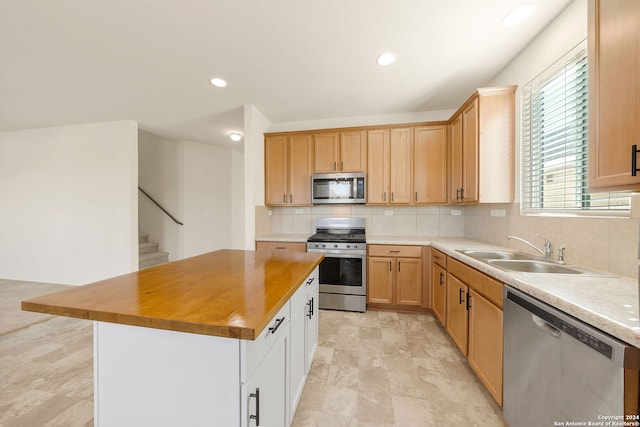 kitchen with appliances with stainless steel finishes, tasteful backsplash, sink, a kitchen island, and butcher block counters