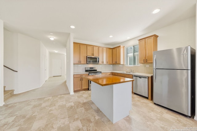 kitchen with sink, stainless steel appliances, tasteful backsplash, light colored carpet, and a kitchen island