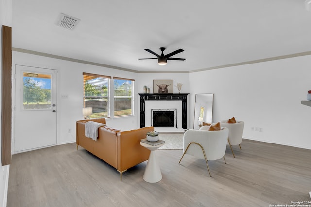 living room featuring light hardwood / wood-style floors, ceiling fan, and crown molding