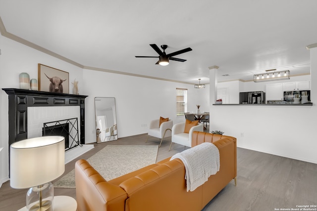 living room featuring a fireplace, crown molding, light hardwood / wood-style flooring, and ceiling fan