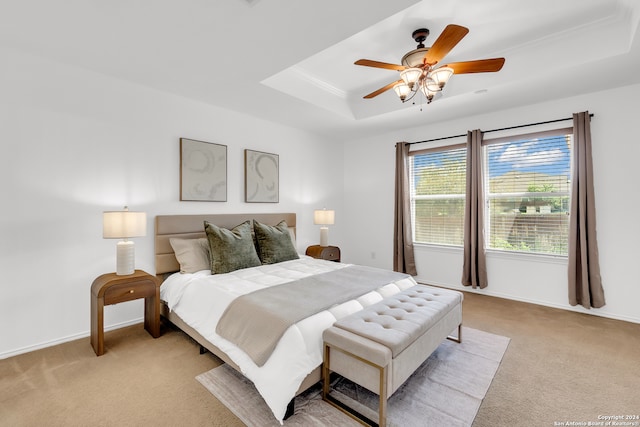 bedroom with ceiling fan, light colored carpet, crown molding, and a tray ceiling